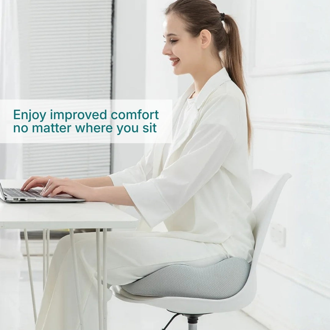 An image showing a woman using a adjustable memory foam seat cushion while working at a desk.