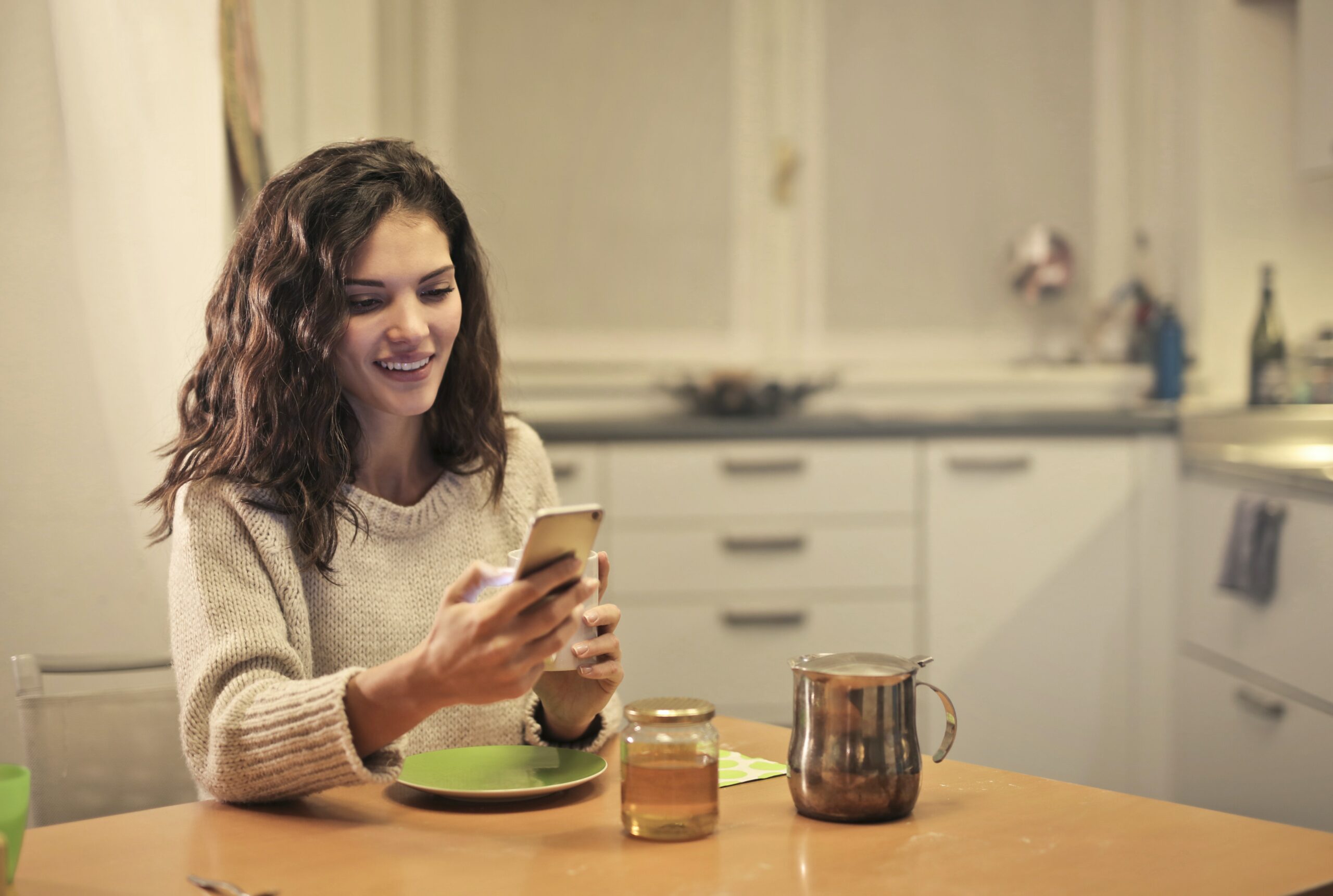 woman-holding-phone-while-having-tea